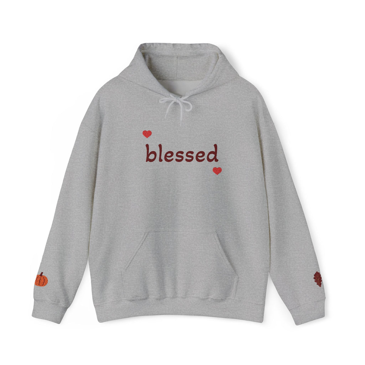 A light gray heather pullover hoodie with 'blessed' written in dark red script across the chest, flanked by two small red hearts. The hoodie features a white drawstring hood, a front kangaroo pocket, a small orange pumpkin graphic on the left sleeve cuff, and a small red heart graphic on the right sleeve cuff.