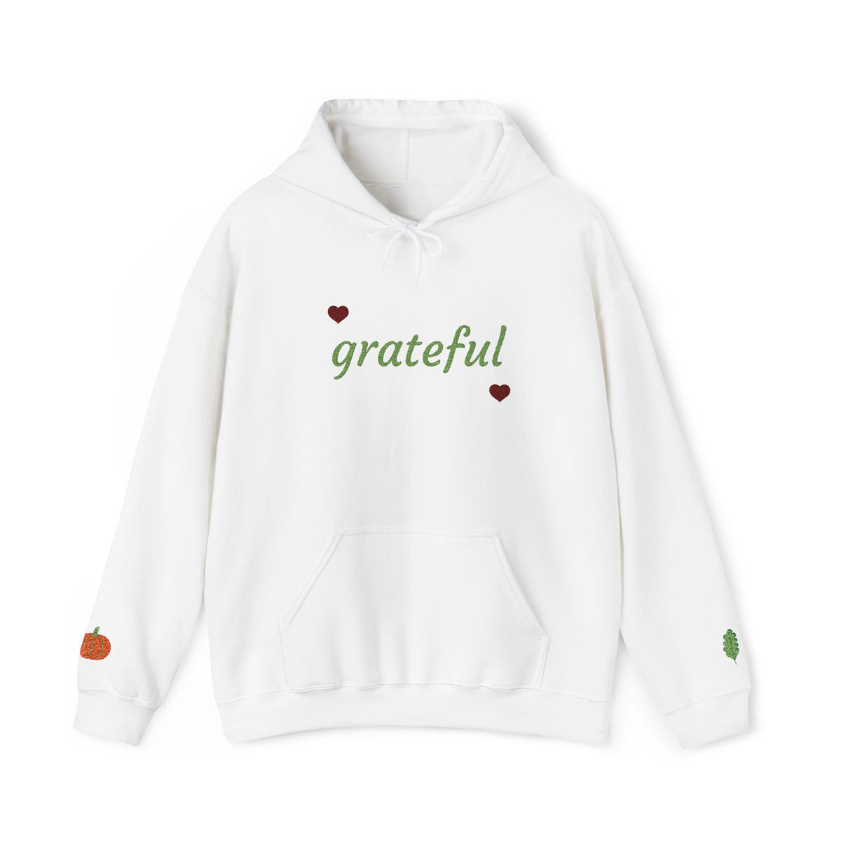 A white pullover hoodie with 'grateful' written in green cursive across the chest, flanked by two small red hearts. The hoodie features a front kangaroo pocket, white drawstrings, a small orange pumpkin graphic on the left sleeve cuff, and a small green leaf graphic on the right sleeve cuff.