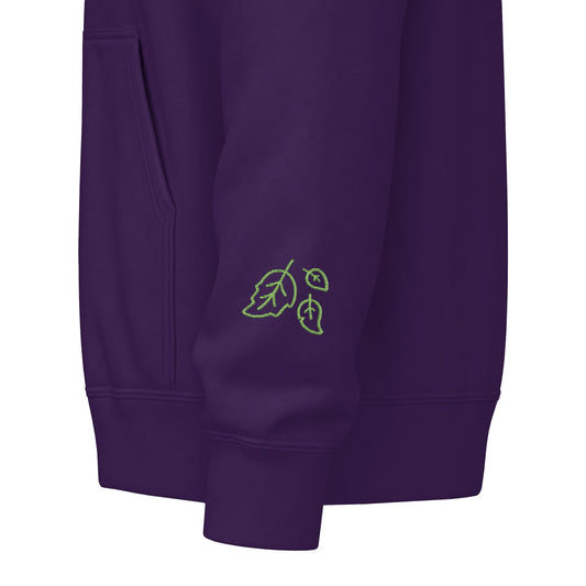 Close-up of a crewneck sweatshirt sleeve showing the ribbed cuff, side pocket seam, and a small tonal embroidered logo near the lower cuff on a white background.