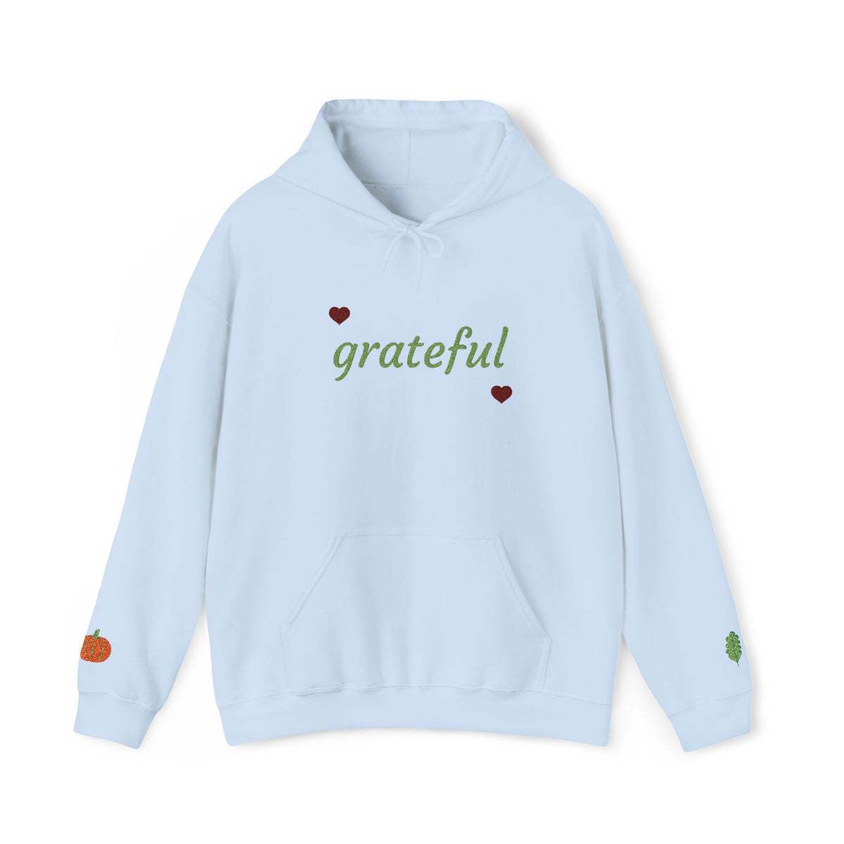 A light blue pullover hoodie with 'grateful' written in green script across the chest, flanked by two small red hearts. The hoodie features a drawstring hood, a front kangaroo pocket, and small decorative graphics on both cuffs, including a small orange pumpkin on the left cuff and a green leaf on the right cuff.